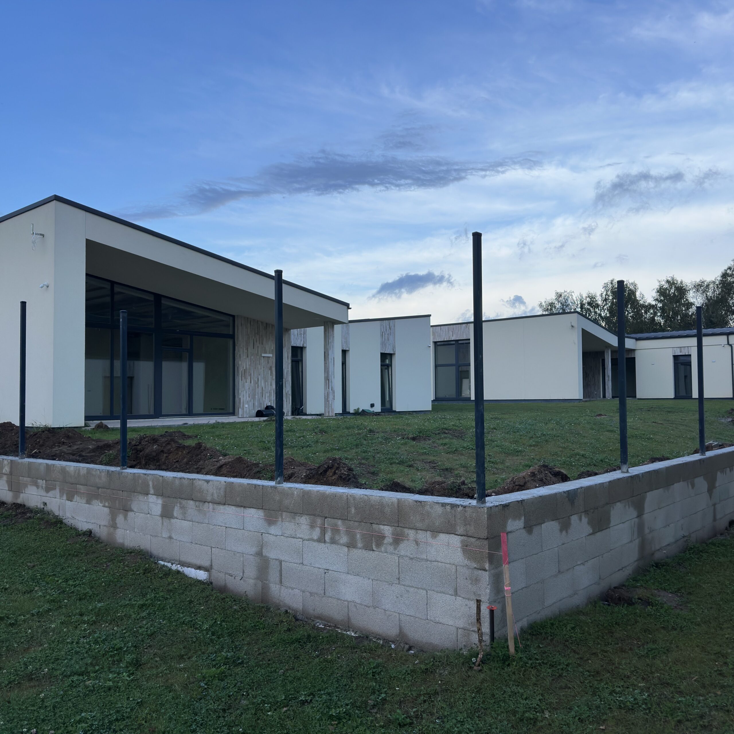 Atraminės sienelės įrengimas šlaito sutvirtinimui prie modernaus gyvenamojo namo